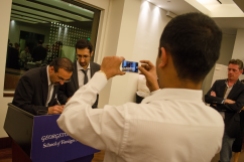 A man takes a picture of his friend as he gets his book signed by Mehran Kamrava.