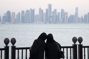 Two women look out from the Pearl-Qatar at the Doha skyline. 