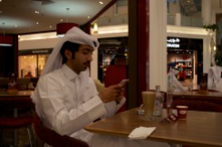 A man drinks coffee and attends to his smartphone at Häagen-Dazs in Landmark Mall in Doha.